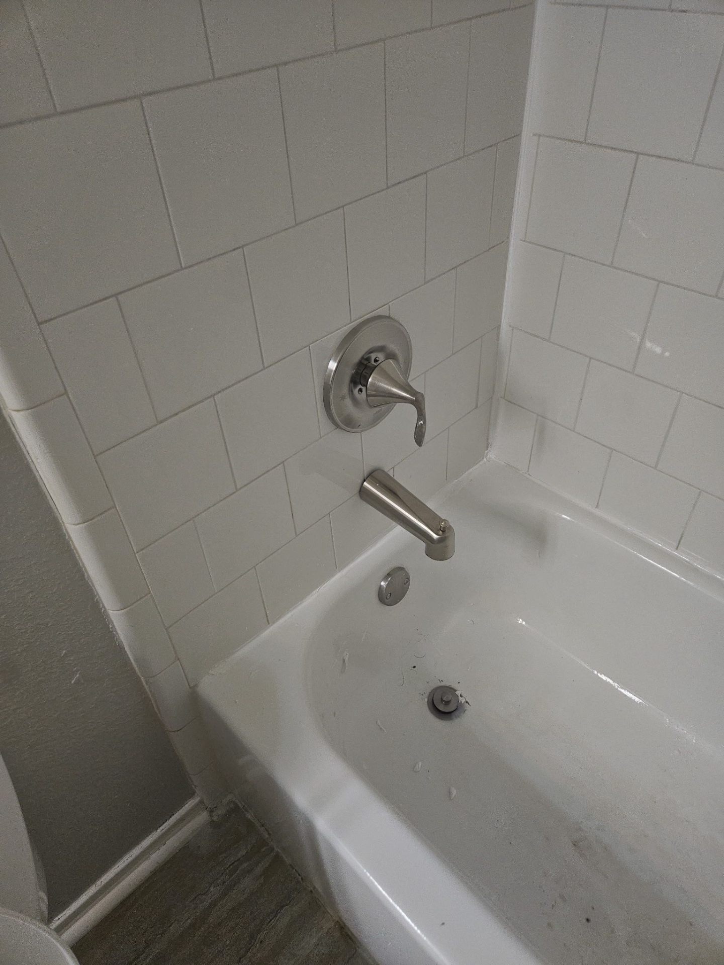 Re-caulked white tile shower surround and bathtub