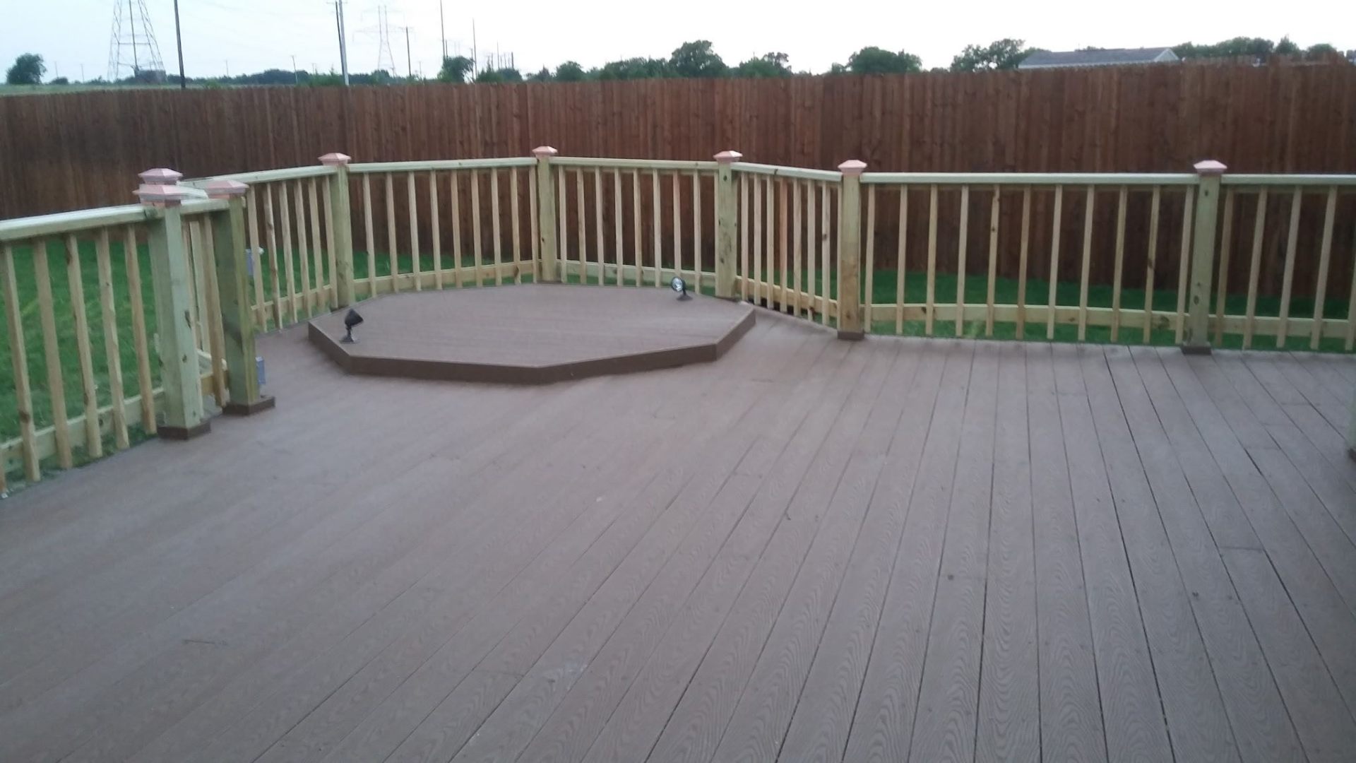 Newly built backyard composite deck with wood railing