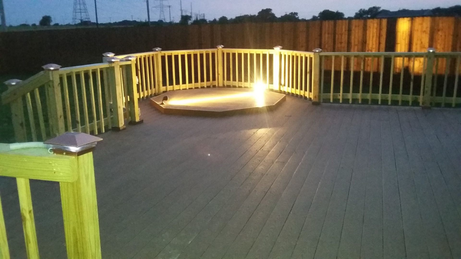 Custom wood deck with solar post-cap lighting at dusk
