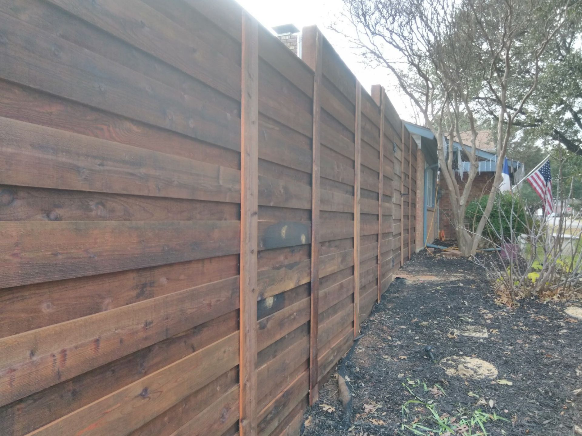 Horizontal plank wood fence along a side yard