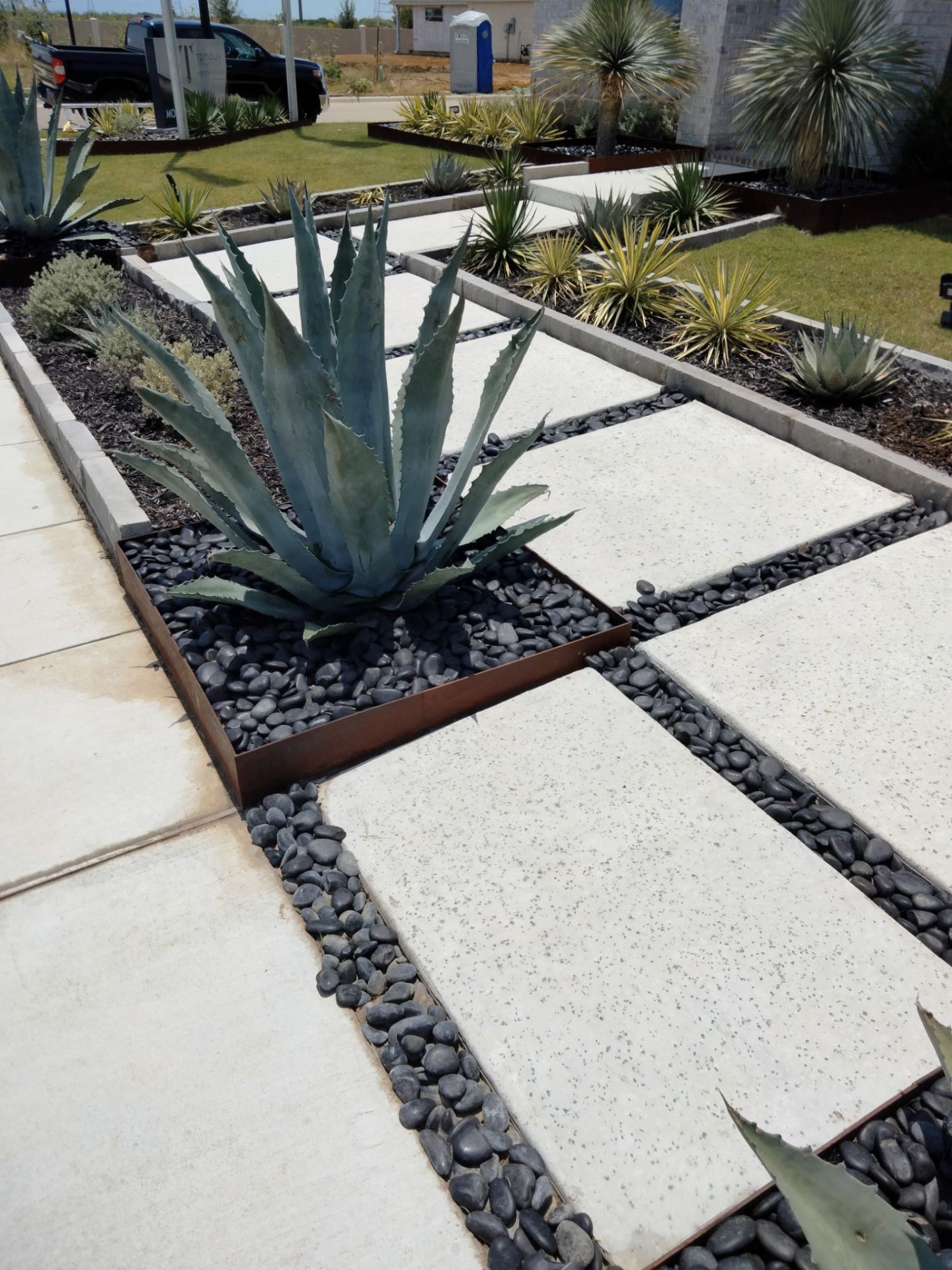 Modern landscaping with concrete pavers, river rock and agave plants